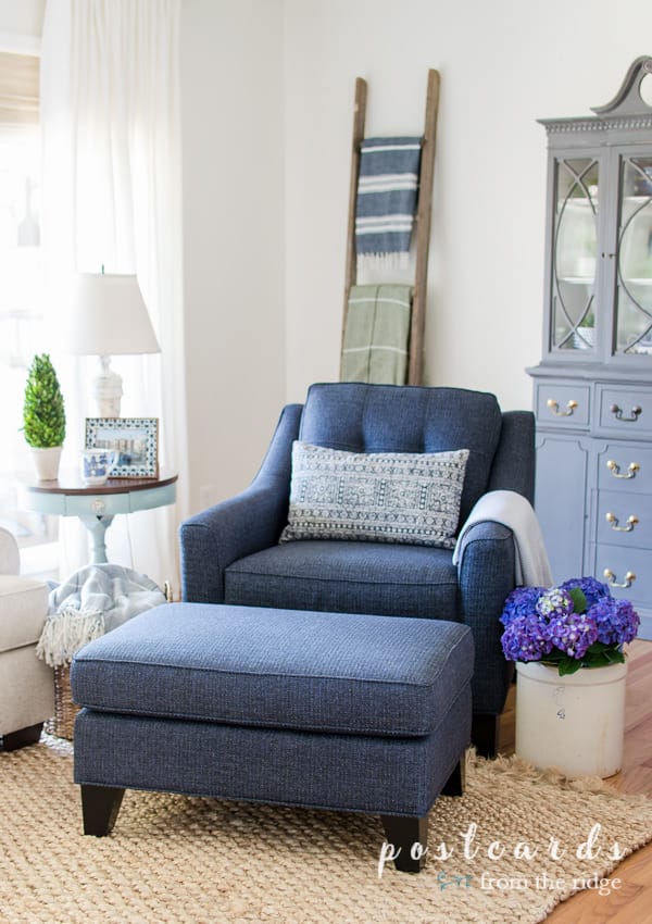 客厅里有本杰明·摩尔白色的鸽子墙，蓝色的椅子和脚凳