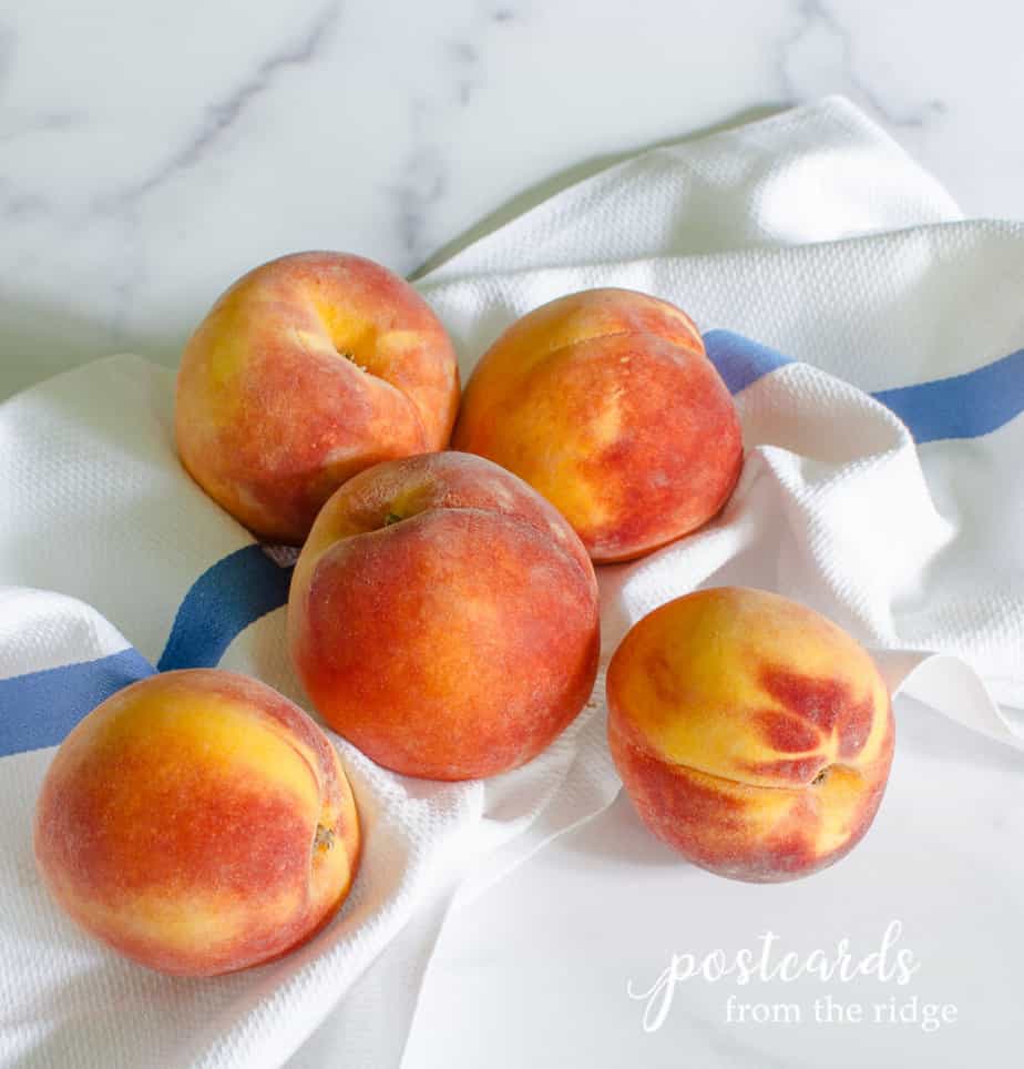 新鲜的桃子放在蓝白条纹的厨房毛巾上