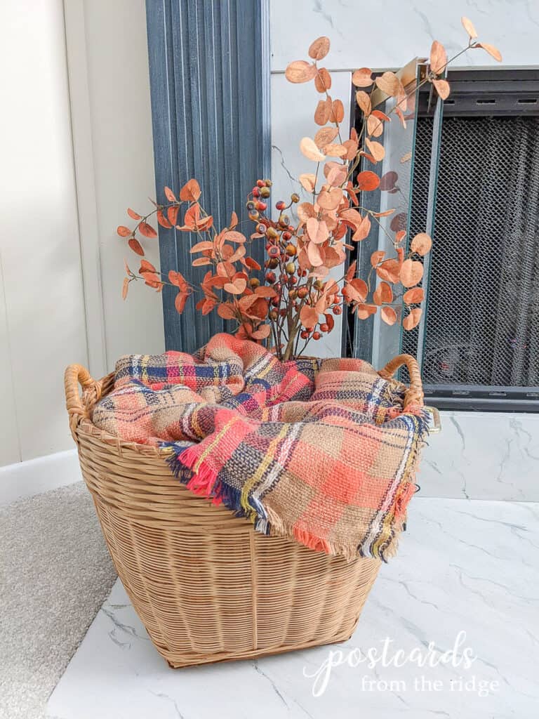 大柳条篮与橙色格纹毯子围巾和秋天的树枝